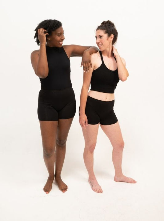 Two women wearing plant-based, comfy, and stretchy boyshorts in black color. Moisture-wicking and breathable features were provided by the plant-based material.
