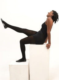 The woman is laughing and sitting on the white blocks. She's wearing the black RevoTights from CLOECO brand. Super breathable, durable and itch-free.